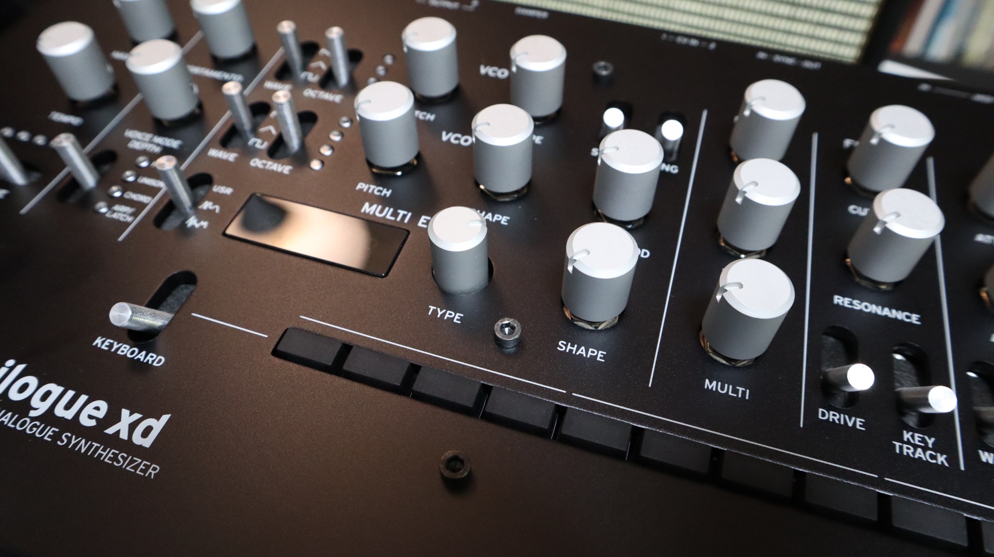 Close-up of a black Korg Minilogue XD with silver replacement knobs installed.